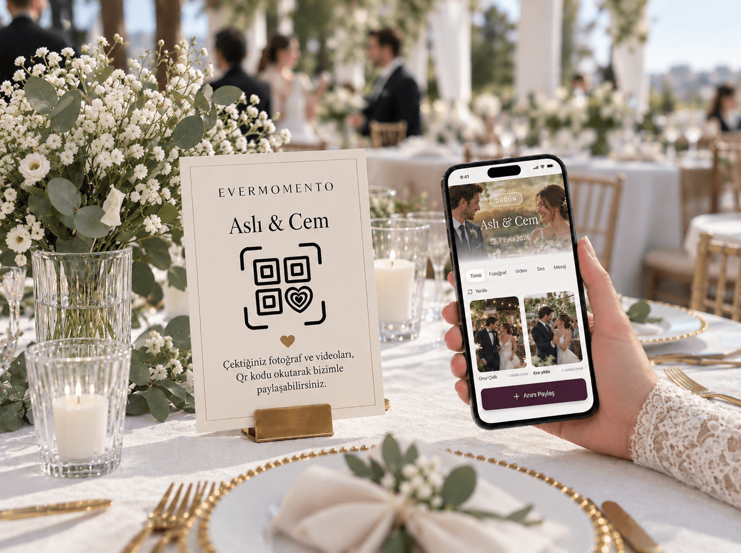 Masada QR albüm kartı, elde yükleme ekranı açık telefon ve önde polaroid fotoğraflar